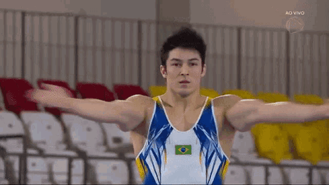 a young man in a blue and white leotard with a brazilian flag on it is doing a trick on a trampoline