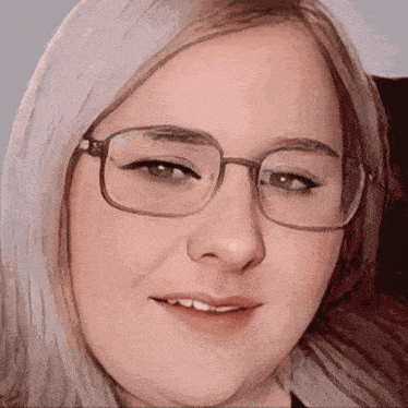 a close up of a woman wearing glasses with a smile on her face