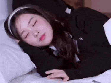 a girl in a school uniform is sleeping on a bed