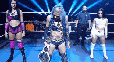 a group of female wrestlers are standing in a ring .