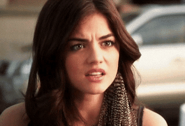 a close up of a woman making a funny face while wearing a scarf .
