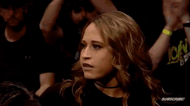 two female wrestlers are standing next to each other in a dark room .