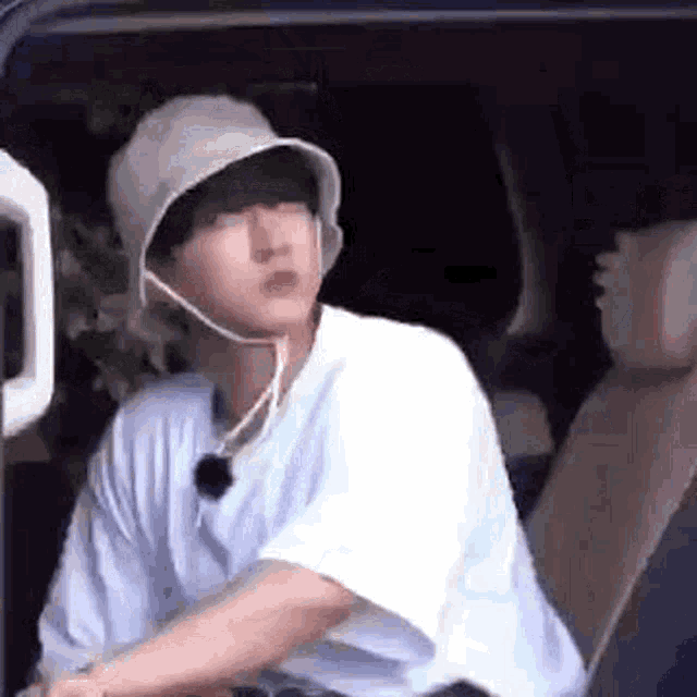 a young man wearing a hat and a white shirt is sitting in a car .