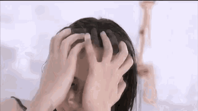 a woman is washing her hair in a bathtub while holding her head with her hands .