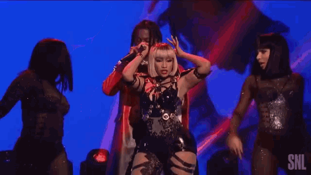 a group of people are dancing on a stage in front of a pink backdrop .