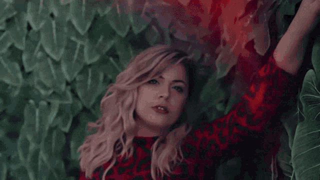 a woman in a red dress is laying in front of a green wall .