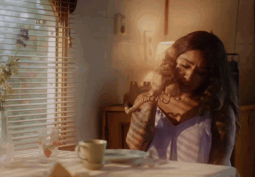 a woman sitting at a table talking on a telephone