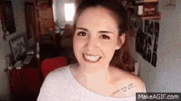 a woman with a tattoo on her shoulder is smiling in a living room .
