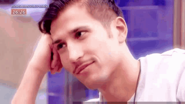 a man is sitting at a table with his hand on his forehead .