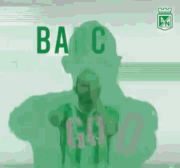 a man with a beard is wearing a green soccer jersey and covering his face with his hands .