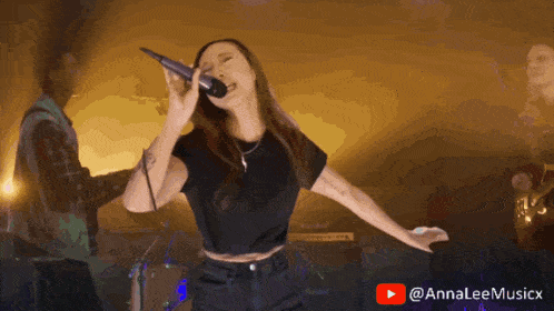 a woman singing in front of a microphone with a youtube logo in the background