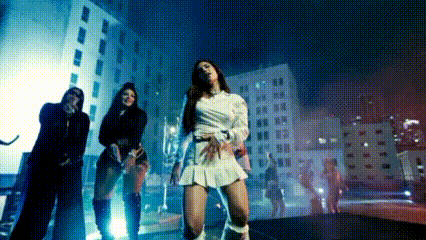 a group of women are dancing in front of a building in a city at night .