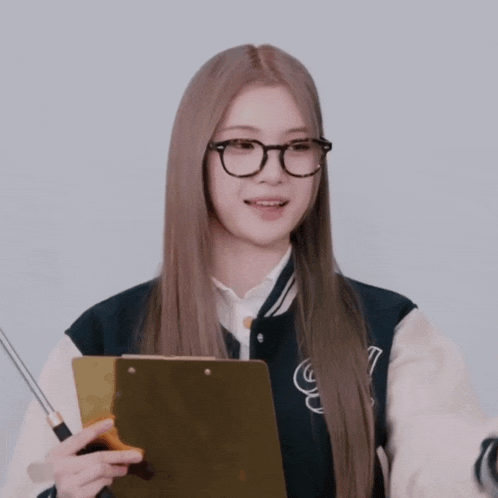 a woman wearing glasses holds a clipboard