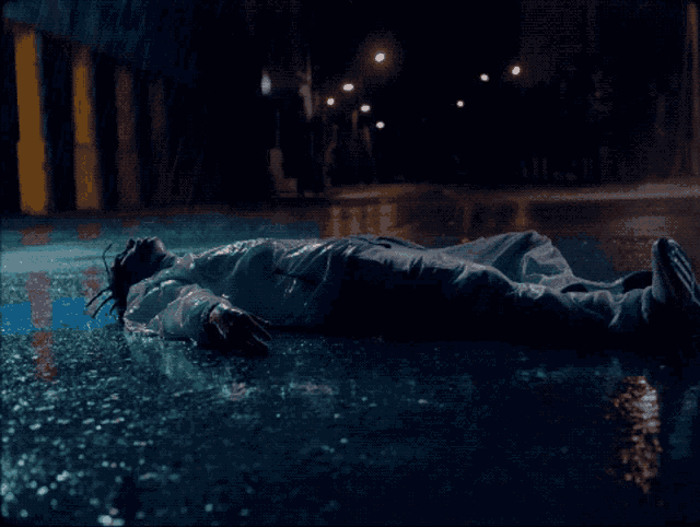 a man laying on the ground in the rain
