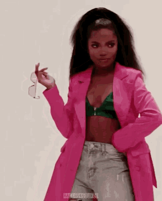 a woman is wearing a pink jacket and holding a pair of sunglasses ..