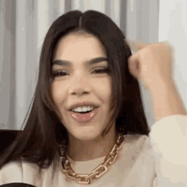 a close up of a woman wearing a gold necklace and a white shirt .