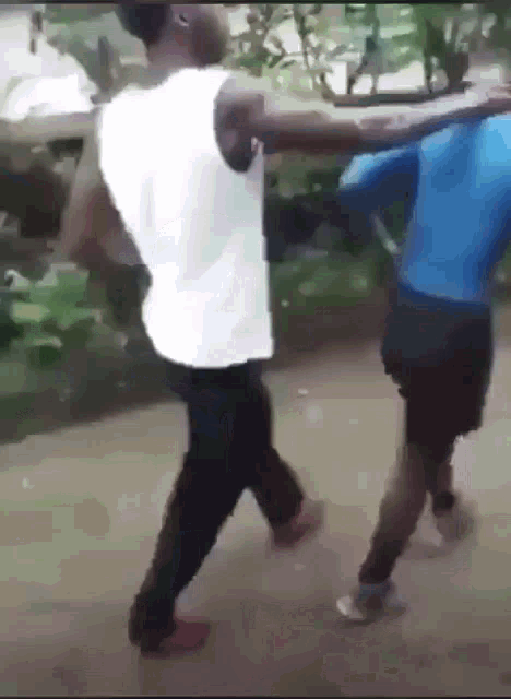 two men are standing next to each other on a dirt road .