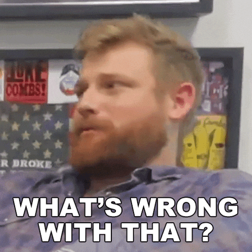 a man with a beard is sitting in front of a wall with stickers on it .