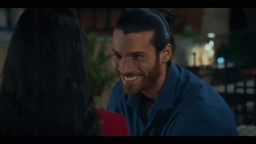 a man with a beard is smiling at a woman in a red shirt