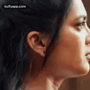a close up of a woman 's face with earrings in her ear .