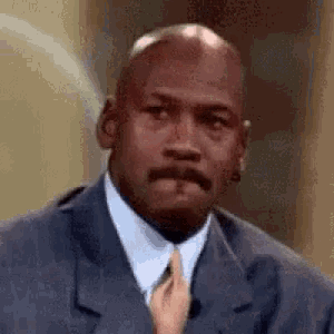 michael jordan is wearing a suit and tie and making a face .