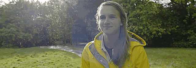 a woman in a yellow raincoat is standing in a field
