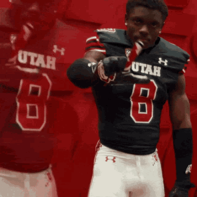 a football player wearing a utah jersey is pointing