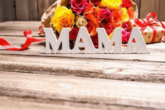 the word mama is on a wooden table next to a bouquet of roses