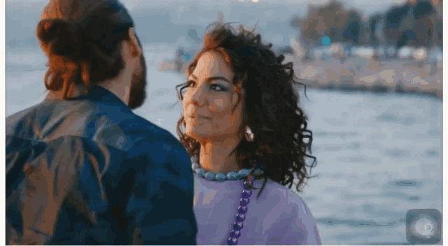 a man and woman are looking at each other near the water
