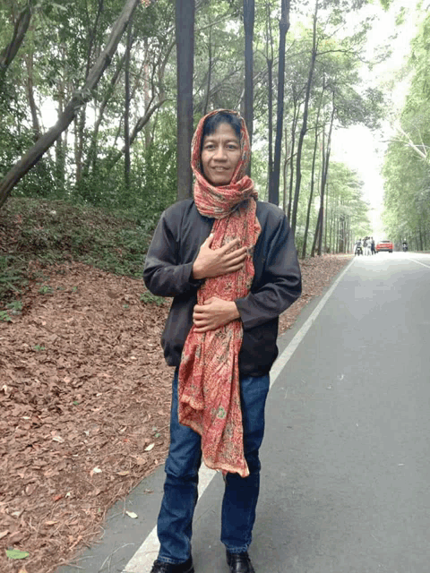 a man with a scarf around his head is standing on a road