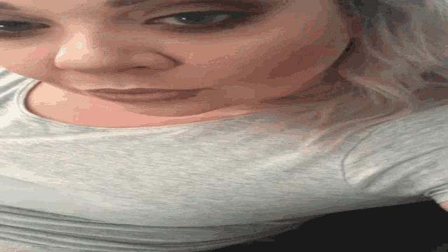 a close up of a woman 's face wearing a gray shirt .
