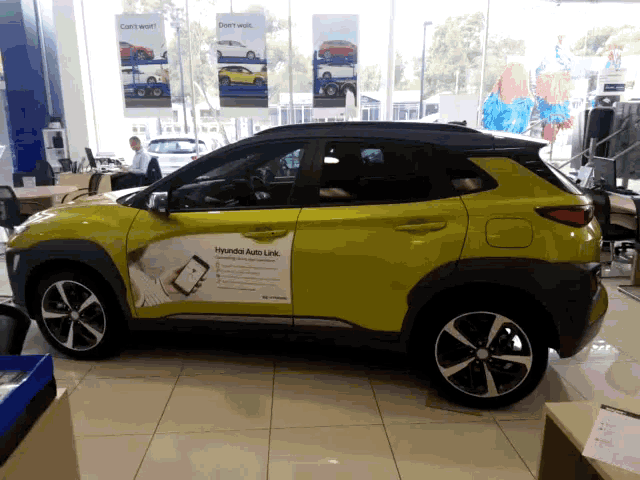 a yellow car with a hyundai auto link advertisement on the side