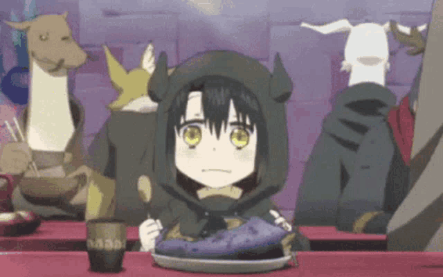 a girl is sitting at a table with a plate of food and a spoon .