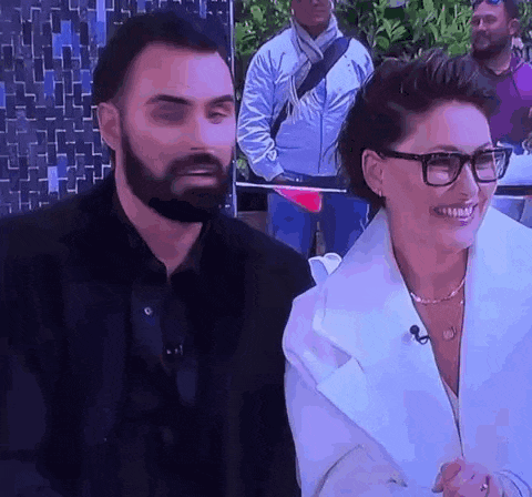 a man with a beard and glasses is standing next to a woman in a white coat .