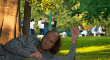 a man is laying under a tree in the park