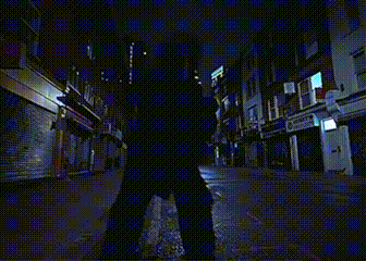 a person walking down a dark street at night with a sign that says ' a ' on it