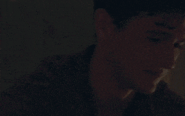 a close up of a man covering his mouth with his hand in a dark room .