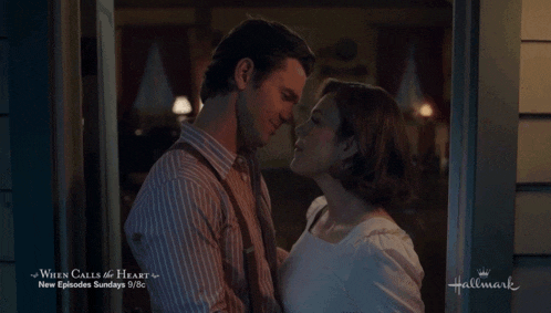 a man and woman kissing in front of a sign that says hallmark