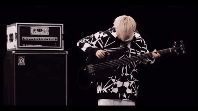 a man playing a bass guitar in front of a ampeg amplifier