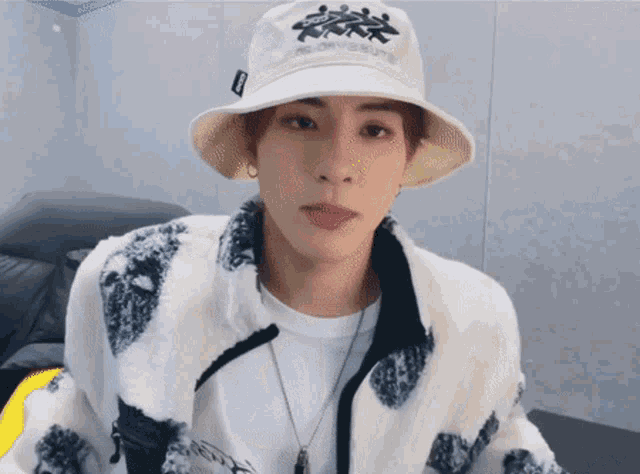 a young man wearing a bucket hat and a jacket with a necklace