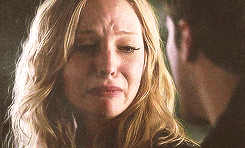 a woman is crying while looking at a man in a dark room .