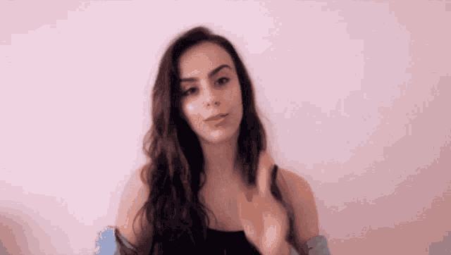 a woman in a black tank top is waving her hand