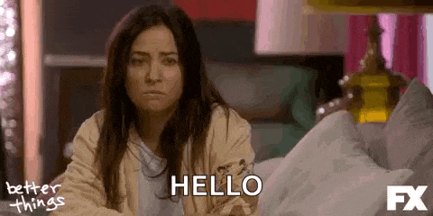 a woman is sitting on a bed talking to someone and saying hello .