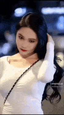 a woman with long black hair is wearing a white dress and a black purse .