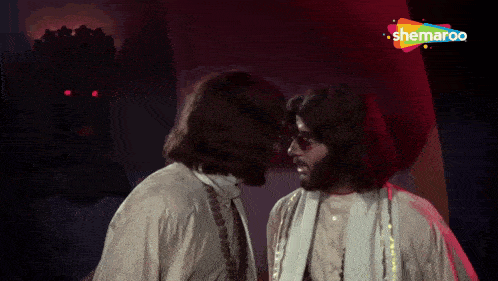 two men are standing next to each other in front of a sign that says ' shemaroo '