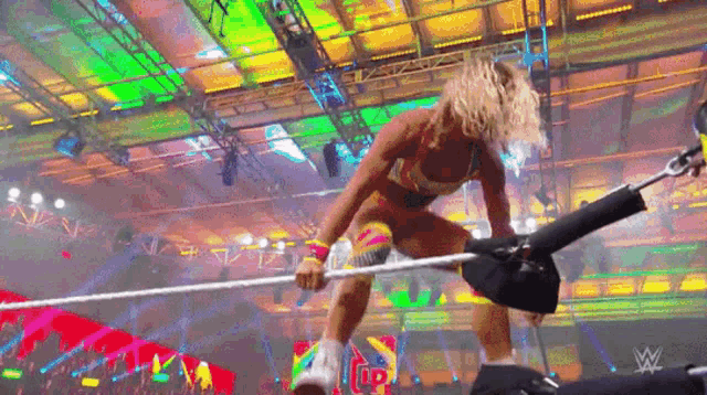 a female wrestler is jumping over a rope in a wrestling ring .