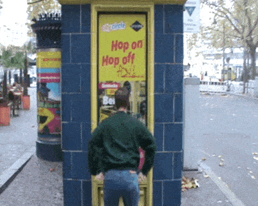 a man urinates in front of a sign that says hop on hop off toll