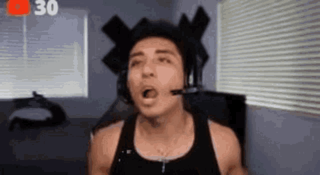a man is wearing headphones and making a funny face while sitting in front of a computer .