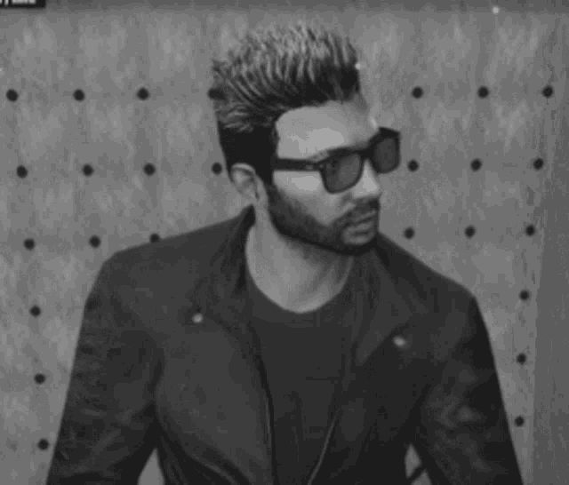 a black and white photo of a man wearing sunglasses and a beard .