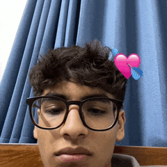 a young man with glasses and a pink heart on his head